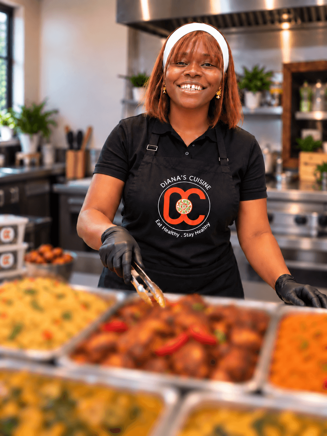 Diana in her kitchen with trays of freshly made Nigerian food